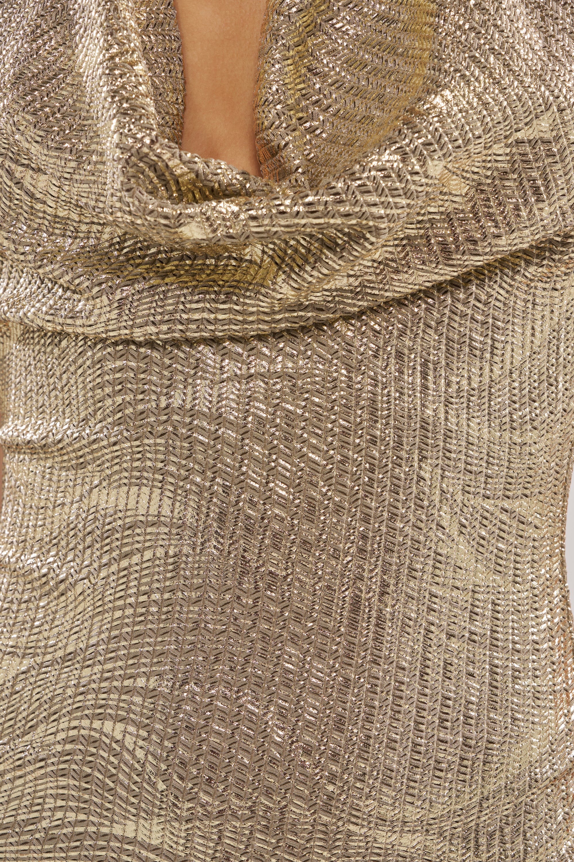 Close-up of the INTO THE NIGHT MINI DRESS in metallic gold, featuring an intricate woven texture and draped halter cowl neckline. The shimmering fabric catches the light, shown here highlighting the upper chest and neck area—perfect for a night out.
