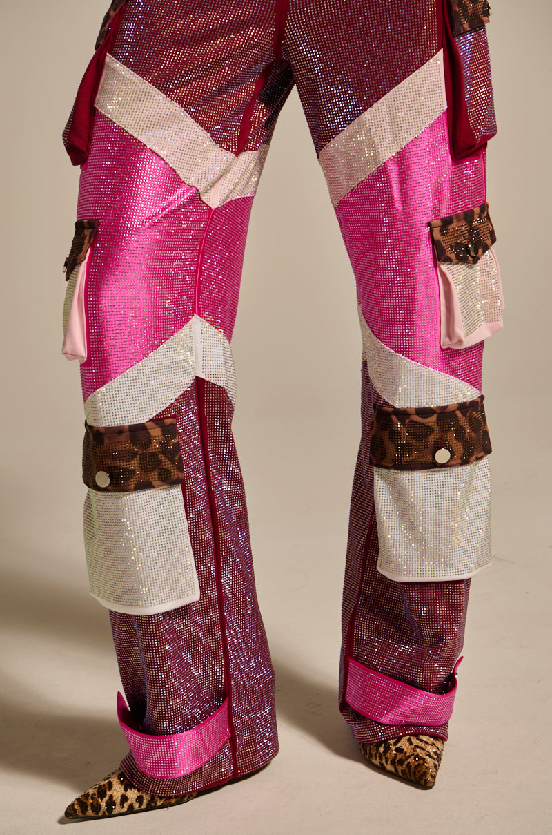 Wearing ONLY THE COOLEST RHINESTONE PANT—sparkly, multi-colored rhinestone pants in pink, red, and silver with animal print pockets and cuffs—paired with pointed leopard print shoes; only the lower body is shown.