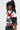 A person with long dark hair in a high ponytail is wearing the OFFICIAL DUTY CROPPED BUTTON DOWN TOP, featuring a color block pattern in red, black, and white. They accessorize with large hoop earrings and subtle makeup while gazing to the left.