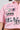 Close-up of the Femme Racing Button Down Poplin Shirt in Pink, featuring intricate embroidered patchwork with text like "Raceway," "A," "79," "World Champions," and "FEM." The racing button-down style is accentuated by a chain necklace partially visible at the neckline.