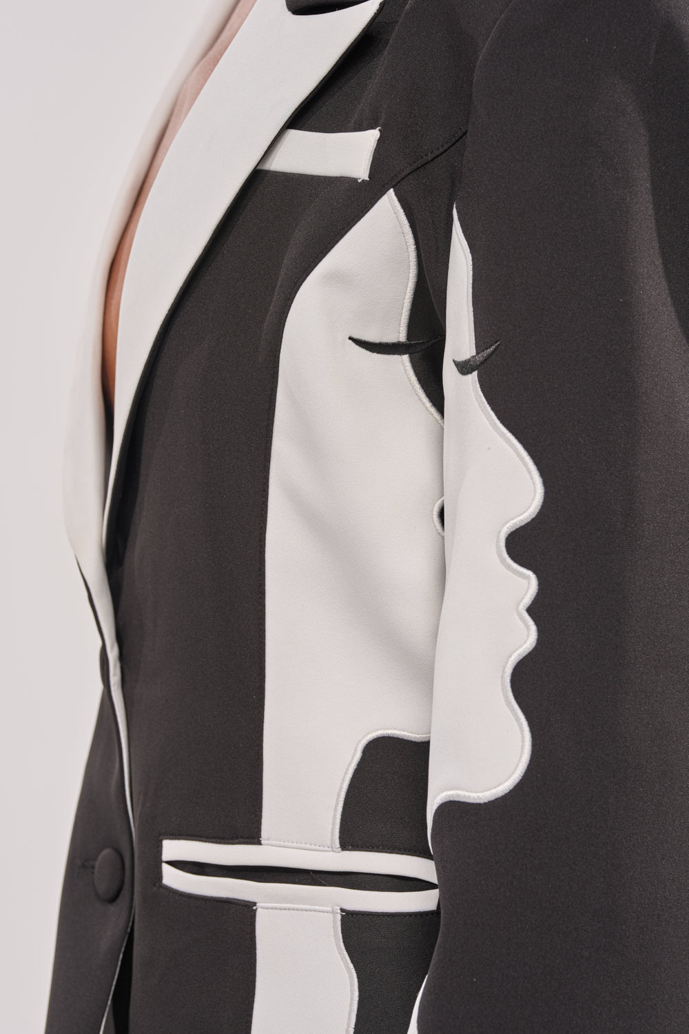 A close-up of the POV GRAPHIC BLAZER, featuring an abstract profile face with closed eyes seamlessly integrated into the fabric—a bold and modern take on power dressing. 10