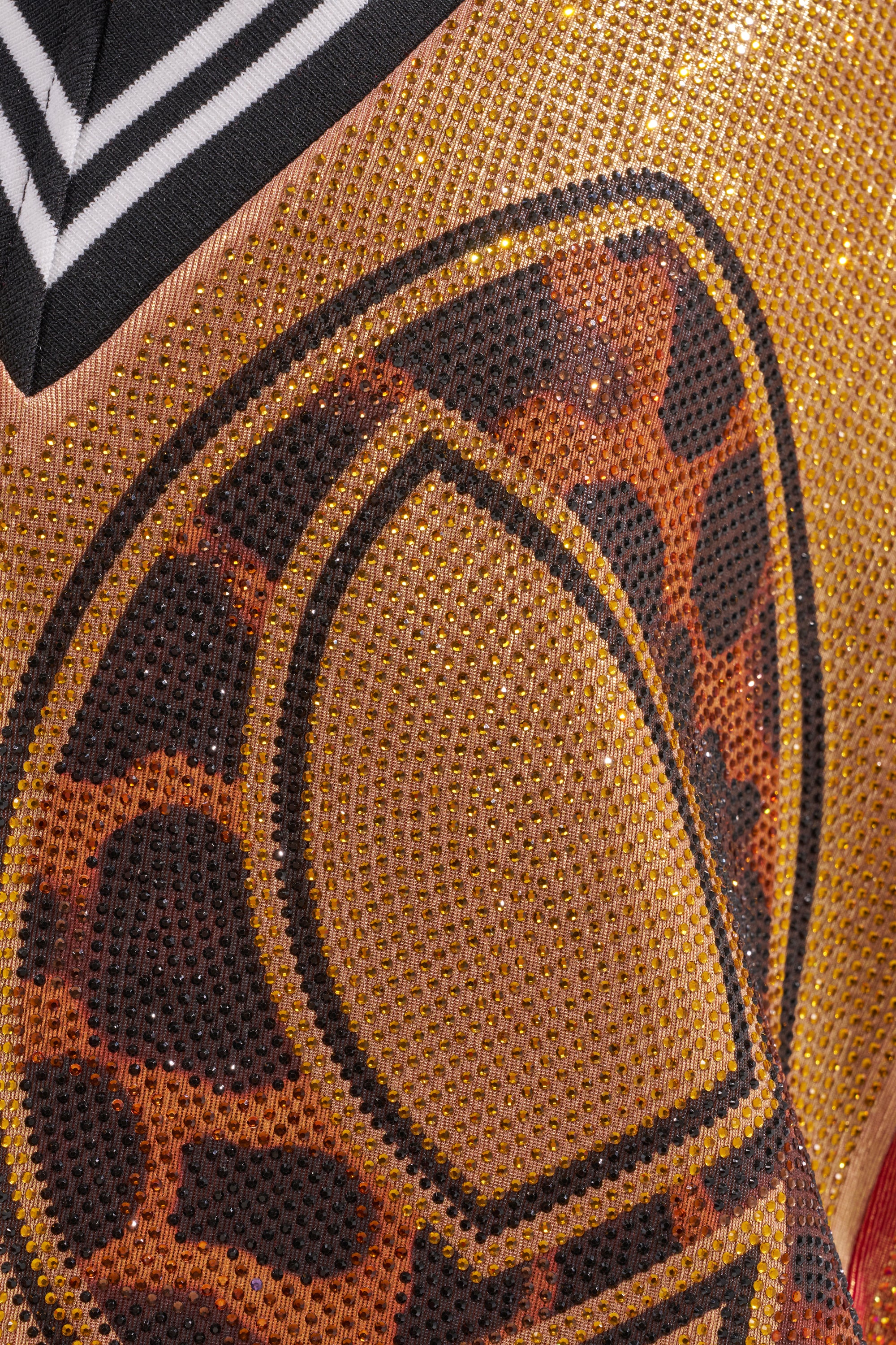 Close-up of the REESE COLORBLOCK RHINESTONE SLEEVELESS JERSEY MINI DRESS, showcasing its bold black, gold, and orange colorblock design with leopard spots and striped black-and-white trim for glamorous courtside style. 8
