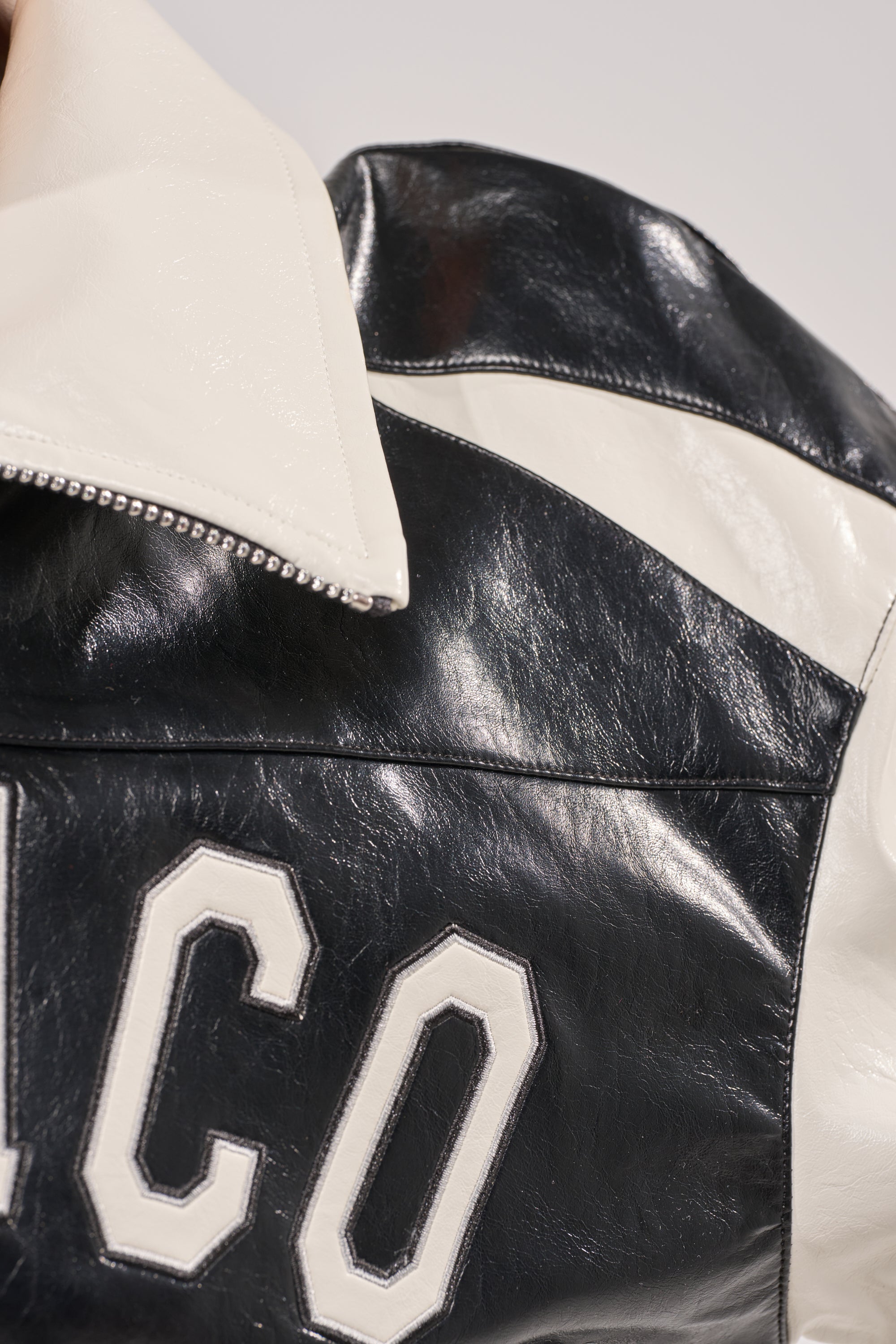 A close-up of the LET'S RACE EMBROIDERED BOMBER in black and white, featuring bold "CO" lettering on the back and a striking white collar that highlights its modern, standout style. 9