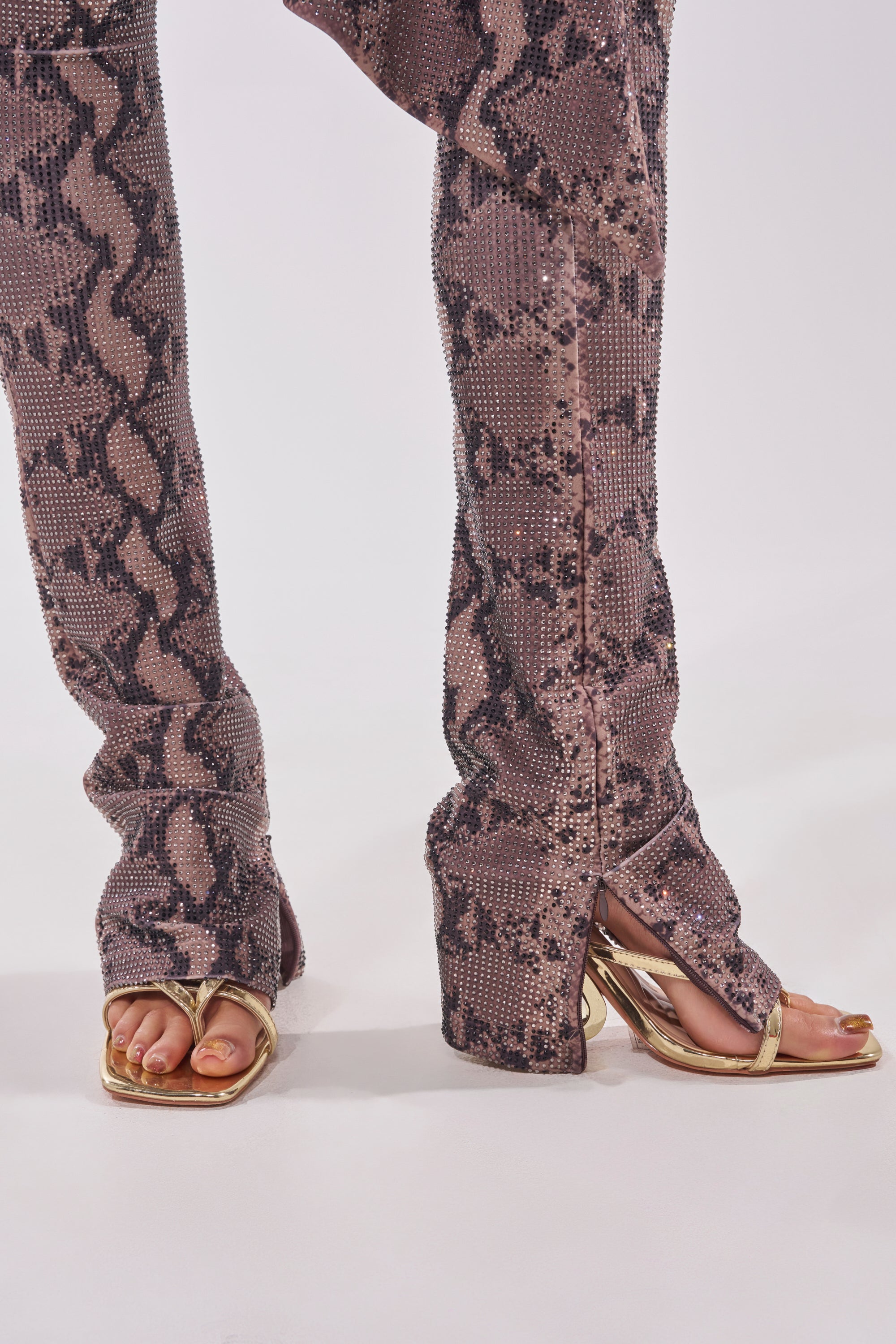 Wearing the VENOM KISS RHINESTONE LEGGING in brown snake print and gold open-toe high-heeled sandals, a person stands against a white background. 8