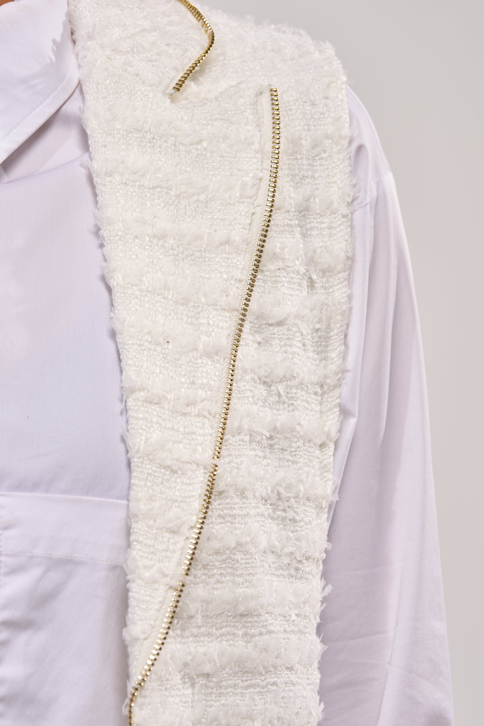 Close-up of the HONEY HONEY SPLIT VEST IN TWEED—a white tweed vest with a decorative gold chain, layered over a white dress shirt. Ideal for modern night-out looks, shown against a light background with only the upper body visible. 5