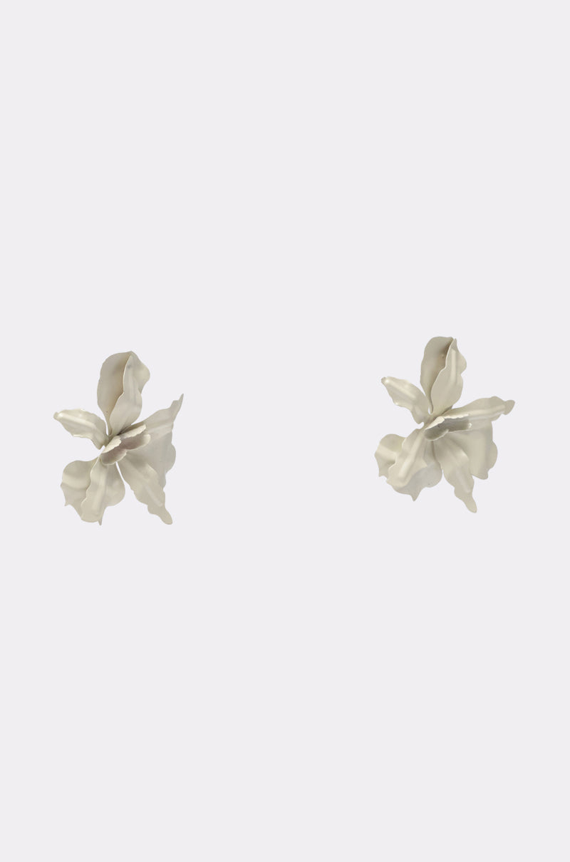 The NEVER SETTLE EARRING features two silver, flower-shaped earrings with wavy, delicate petals that shine beautifully against a plain white background. 3