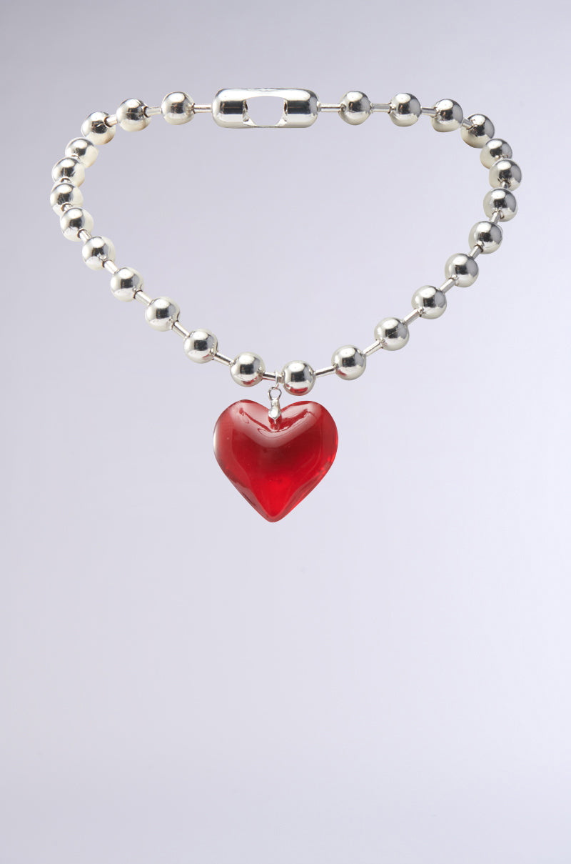 The silver beaded bracelet with a red heart-shaped pendant on a light gray background complements the KEEP MY HEART NECKLACE, adding a chic touch to any layered look.