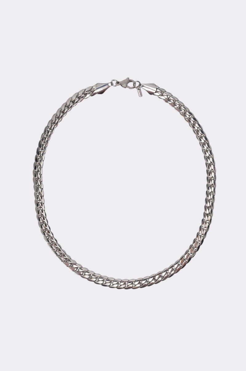 The 16 INCH MIAMI CHAIN 8MM IN SILVER is a stainless steel necklace with a flat curb-style design, displayed in a closed circular shape on a plain light gray background. 0