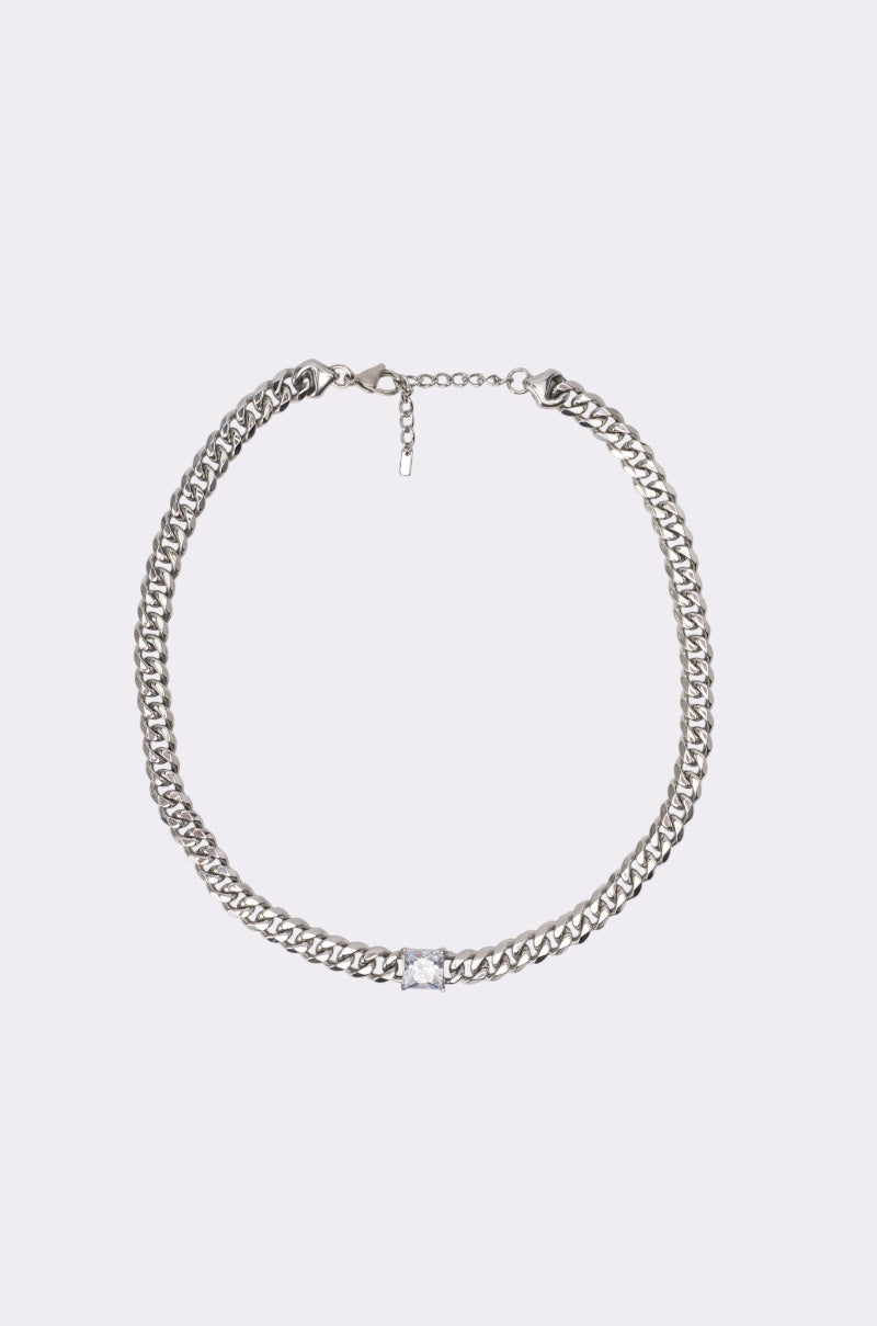 The STAINLESS STEEL SQUARE CZ NECKLACE IN SILVER features a chunky Cuban chain and a central rectangular CZ stone, shown against a simple light background.