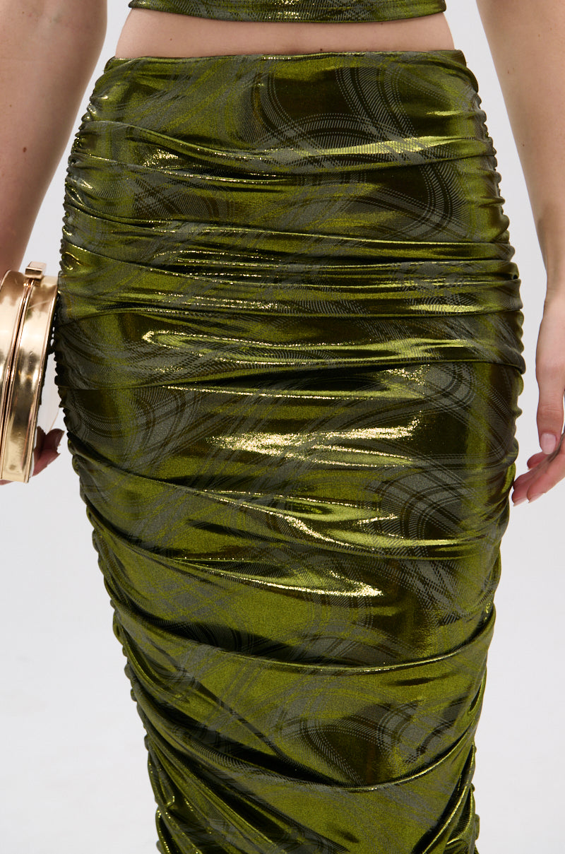 A close-up of a person wearing the TAYLOR METALLIC RUCHED MAXI SKIRT with a subtle wave plaid pattern, paired with a metallic gold clutch, set against a plain white background. 7
