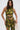 A woman wearing the SEXY CAN I MOCKNECK BLOUSE WITH CUTOUT, a sleeveless green and gold abstract top with metallic knit finish and cut-out details, holds a gold chain handbag against a plain white background.