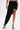 A person wears the KYLIE SLINKY MIDI SKIRT in black with a high-low hem, paired with black high-heeled sandals, a gold bracelet, and a skull tattoo on their thigh. The background is plain white.