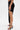A model wears the KYLIE SLINKY MIDI SKIRT, showcasing its ruched waistband, high side slit, and chic high-low hem with black high-heeled sandals. The photo displays only the lower half on a plain white background.