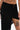 A person wears the KYLIE SLINKY MIDI SKIRT in black, featuring a high slit and ruched waistband, revealing a thigh tattoo, belly button piercing, painted nails, and part of an intricate lower abdomen tattoo.