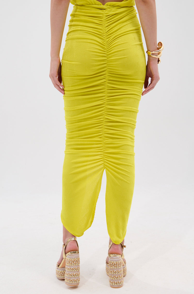 A person wearing a bright yellow TIMELESS MESH MAXI SKIRT and platform woven sandals stands against a plain white background, with only the lower half of their body visible. 4