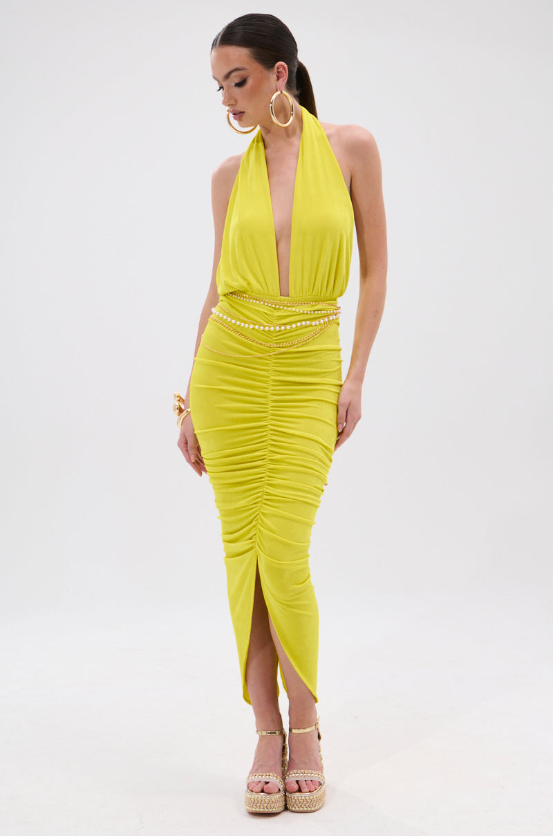 Woman wearing a bright yellow, sleeveless TIMELESS MESH HALTER NECK BODYSUIT with a deep V neckline and ruched detailing. She pairs it with hoop earrings, gold bracelets, and strappy platform sandals against a plain white background. 6