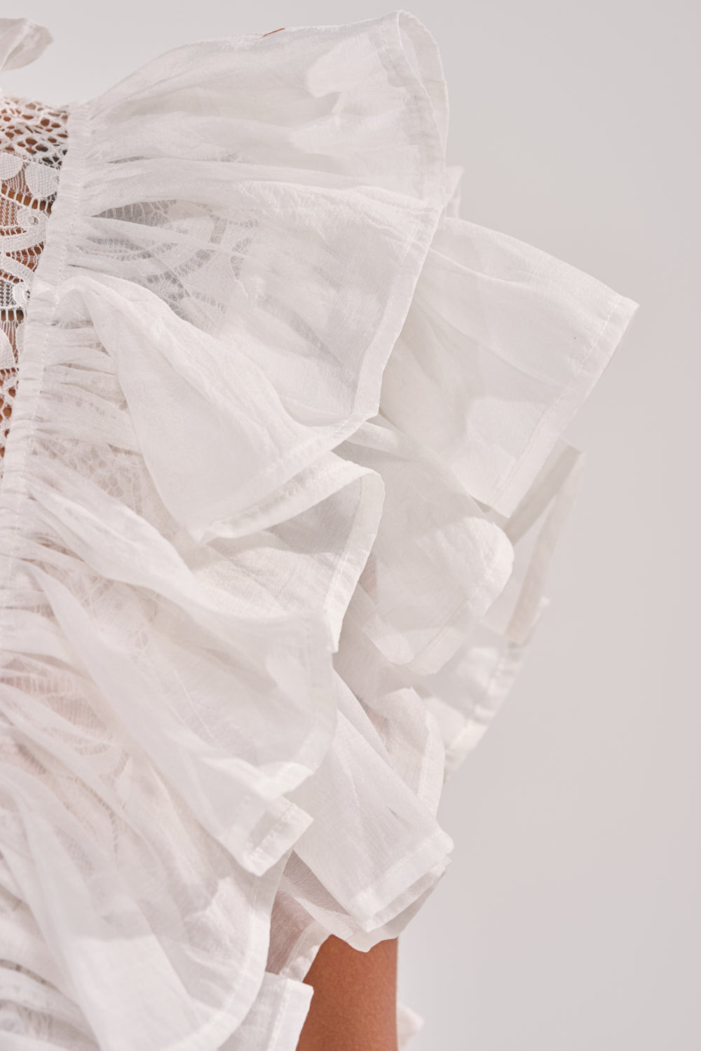 Close-up of the BEST ONE YET LACE BLOUSE, highlighting its ruffled white lace, semi-sheer fabric, and delicate layered structure with intricate detailing—an ideal pick for spring looks. 6