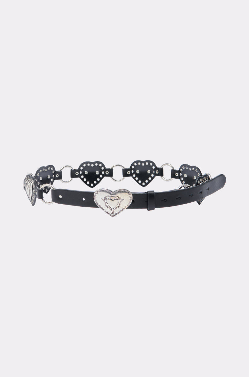 The HEART ON MY SLEEVE PU BELT is a concho-style belt with linked silver heart-shaped pieces, decorative details, and a large central heart-shaped silver buckle.
