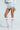 A person poses wearing a cropped knit sweater, SHAKE IT BABY ruffle shorts in baby blue, and knee-high white lace socks paired with white pointed heels, all set against a light blue background.