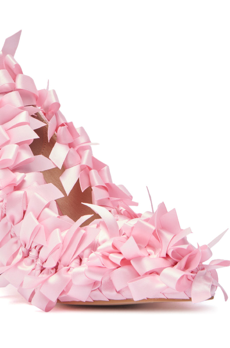 A close-up of the AZALEA WANG STACIA PINK BOW PUMP highlights its satin finish and multiple light pink ribbon bows, giving the heel a textured, decorative look against a white background.