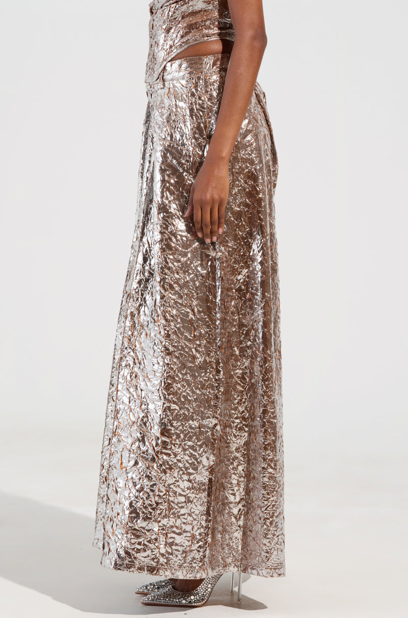 A person wearing the STAR PANT, which features a shiny, metallic texture and a wide-leg silhouette, stands to the side. The pants are long and reflective, paired with sparkling high-heeled shoes. The background is plain and light-colored. 3