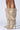 A person wearing the AZALEA WANG STARLEY GOLD RHINESTONE BOOT, which features knee-high metallic faux leather with pointed toes, stands against a plain background.