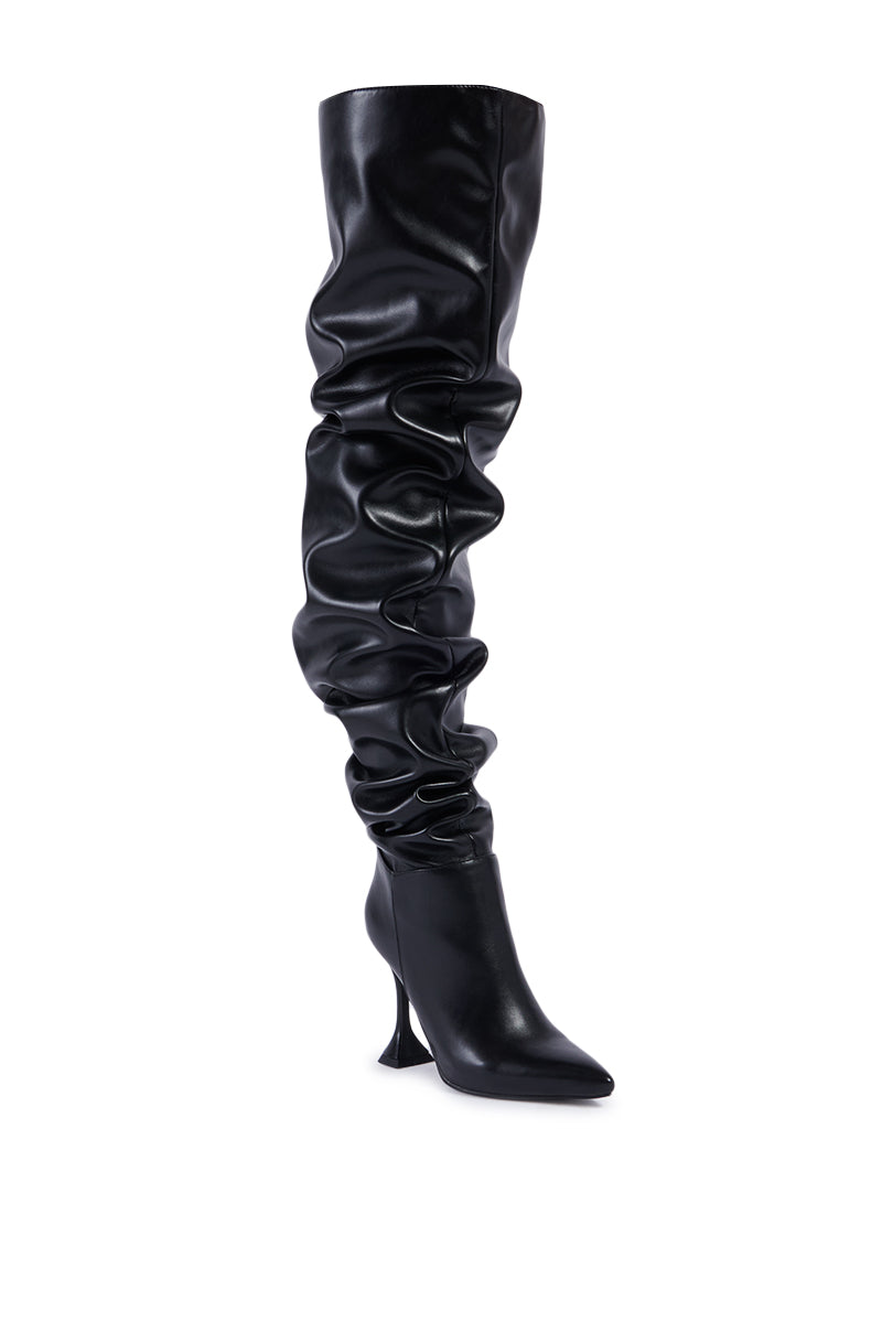 Image of the AZALEA WANG STEPHAN BLACK BOOT, a single black thigh-high, slouchy leather boot with a pointed toe and high stiletto heel. The boot features a ruched design along the leg for a stylish and modern look against a white background.
