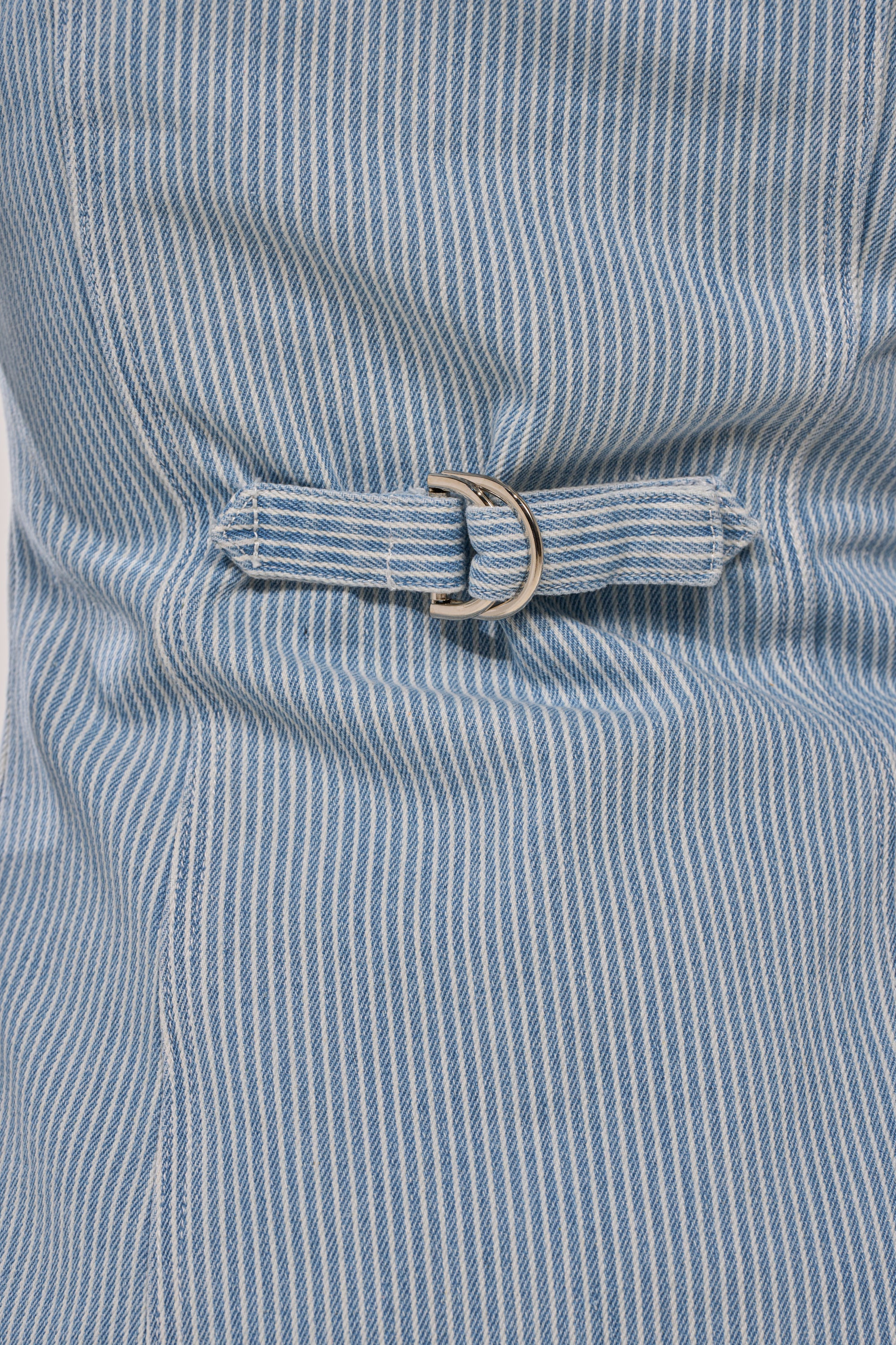 Close-up of the FEEL FREE STRIPE BUTTON DOWN, showcasing blue and white striped fabric, a small belt with a silver D-ring buckle, textured pattern, and gathered seam details. 10