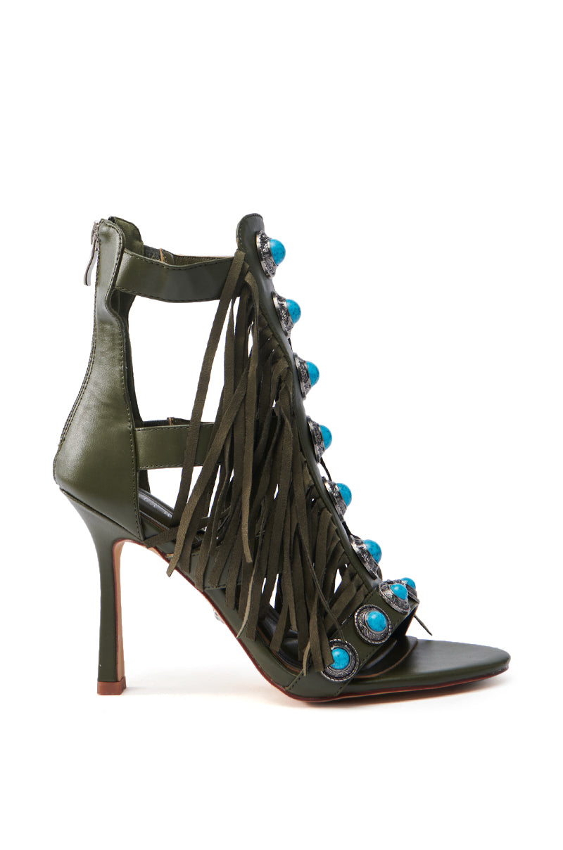 The AZALEA WANG SUMAC OLIVE WESTERN SANDAL is a gladiator-style, high-heeled sandal with fringe on the front, turquoise stone embellishments, faux leather material, a back zipper, slender heel, and open-toed design.
