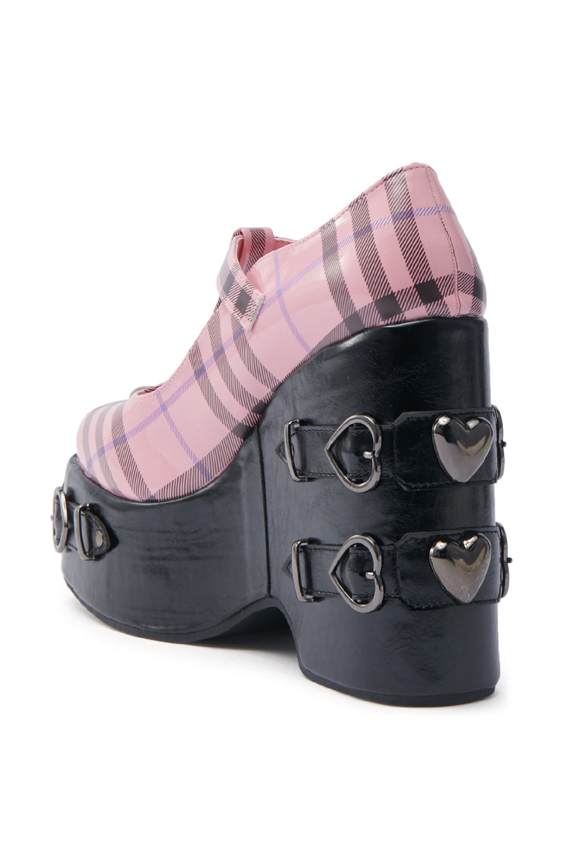 The SWEET APATHY PINK HEART WEDGE PUMP features a pink plaid pattern with a black base, complemented by decorative black straps and silver heart-shaped buckles. The Mary Jane strap enhances its bold, stylish design. 4