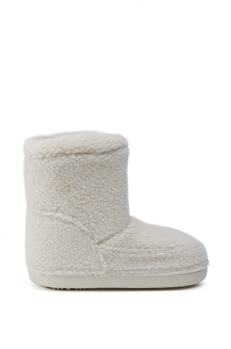 The AZALEA WANG SWEETING WHITE SHERPA BOOTIE is shown as a single, cozy, cream-colored fuzzy slipper boot against a plain white background. It showcases a soft, textured exterior with an ankle-high shaft and a flat sole.