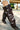 Outdoors on a sunny day, a person wears distressed denim shorts and dramatic, oversized chocolate brown AZALEA WANG SWELCIE thigh-high boots with folded and snap details.