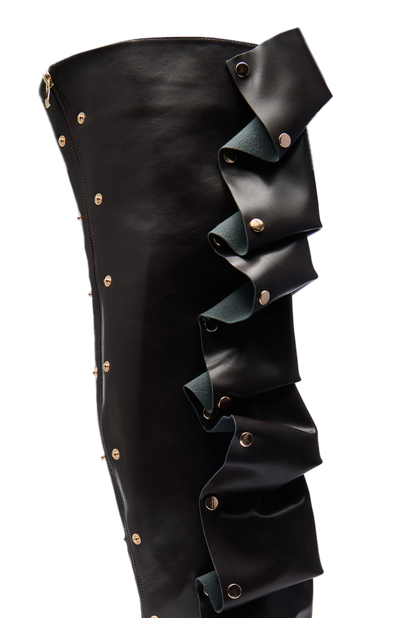 Close-up of the AZALEA WANG SWELCIE Chocolate Brown thigh high boot, featuring a pointed toe, folded and snap detail, with ruffled layers and metallic studs. Contrasting inner lining visible within the ruffles. 7