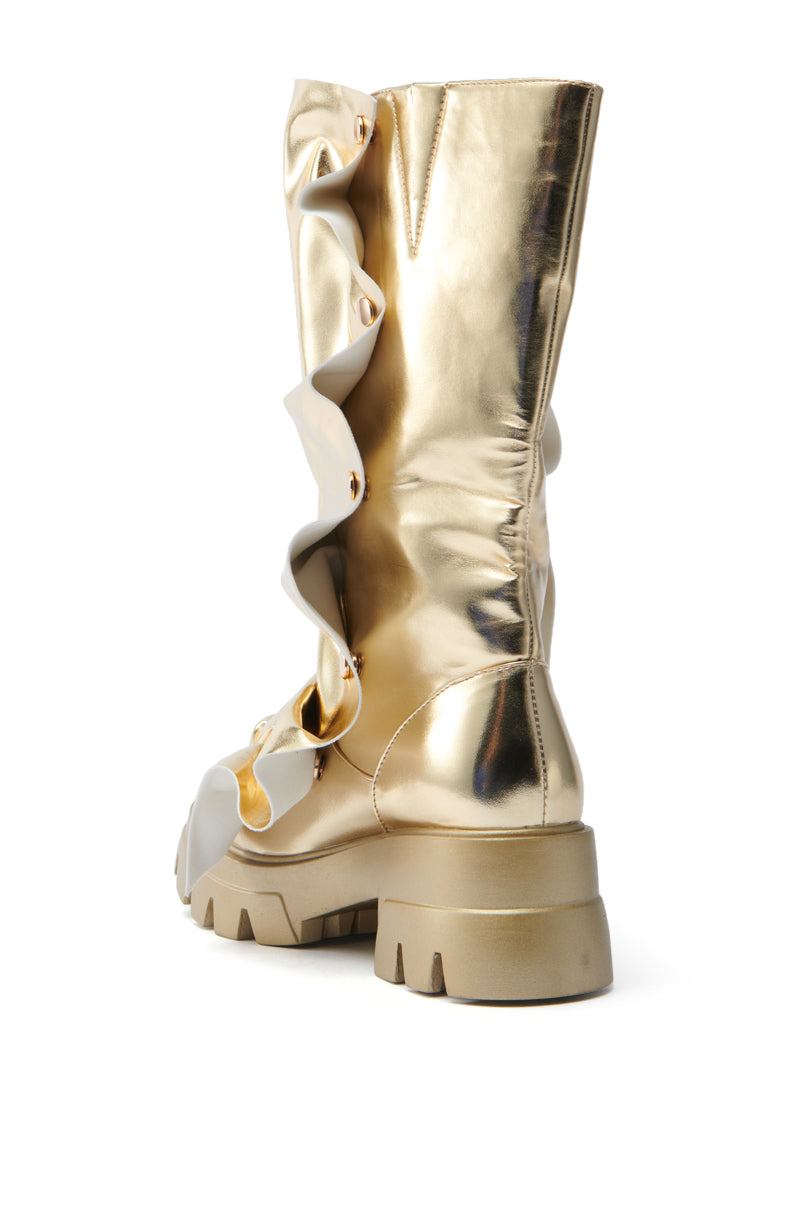 The AZALEA WANG SYBEL BUTTON GOLD FLAT BOOTIE features a platform lug sole, decorative diagonal ruffles, and shiny metallic gold faux leather that beautifully reflects light when viewed from the back.
