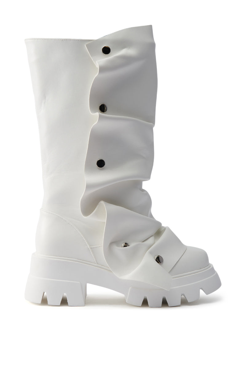The AZALEA WANG SYBEL WHITE SNAP DETAIL BOOTIE is a white, knee-high boot with a platform lug sole, ruched leather, and black snap buttons running irregularly down the side.