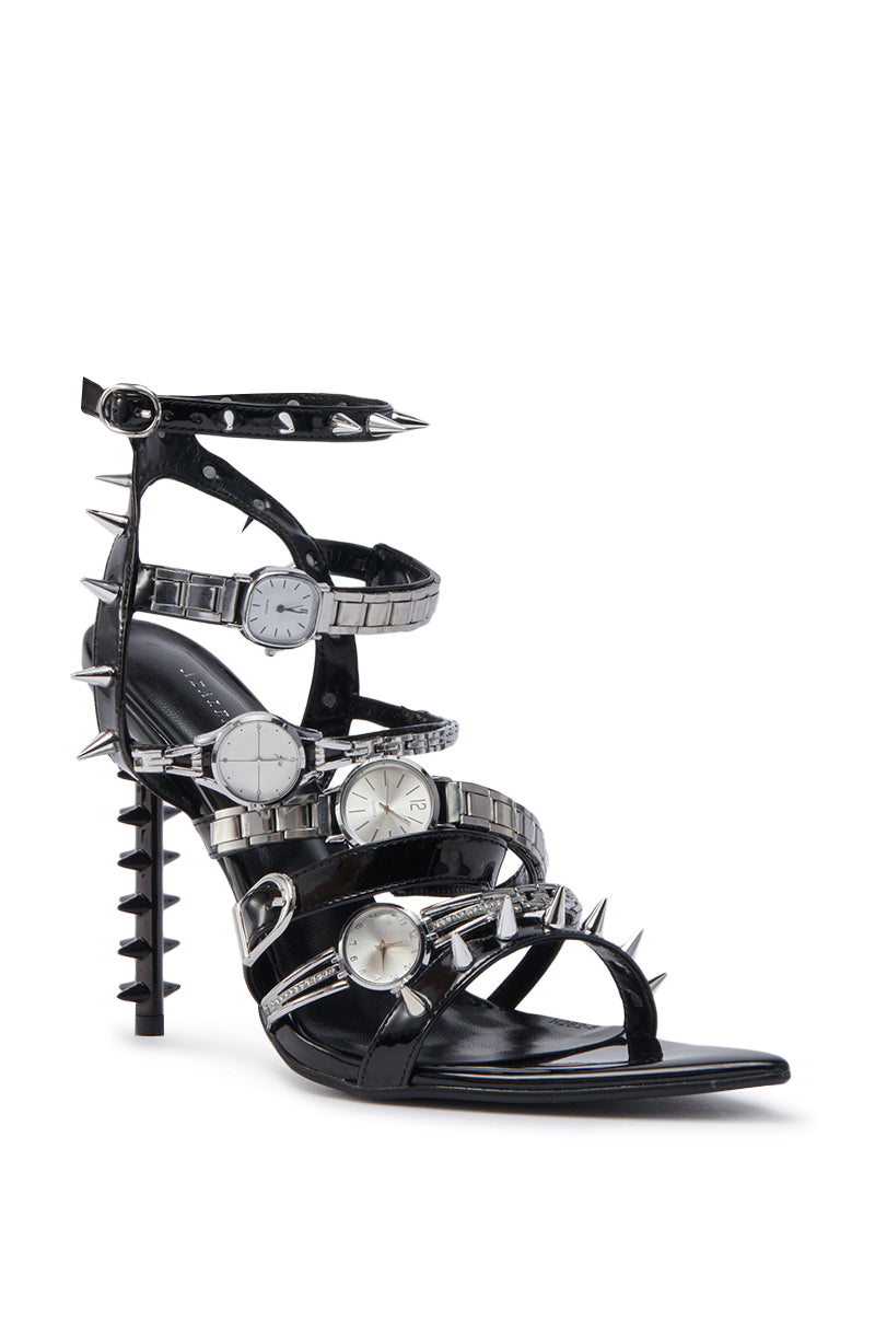 The AZALEA WANG SYDONDIA BLACK WATCH SHOE STILETTO SANDAL is crafted from patent faux leather and features multiple silver watchbands with round watch faces as adjustable ankle straps, plus metal spikes on the heel, ankle, and straps.