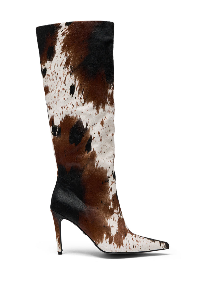 The AZALEA WANG SYREALI COW STILETTO BOOT is a knee-high, pointed-toe stiletto featuring a striking brown, black, and white cow print pattern. 3