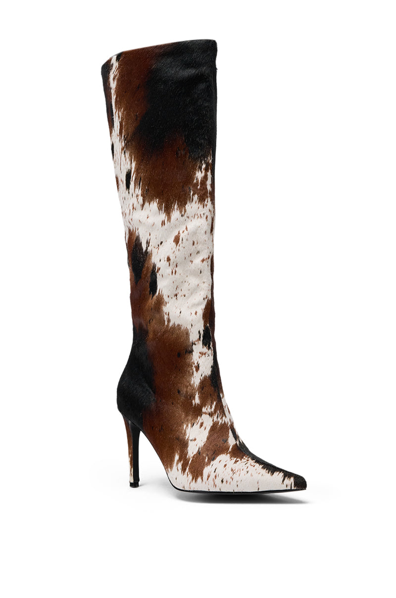 The AZALEA WANG SYREALI COW STILETTO BOOT is a tall, knee-high boot with a pointed toe, bold brown, black, and white cow print, textured fur-like finish, and stiletto heel for standout style. 4