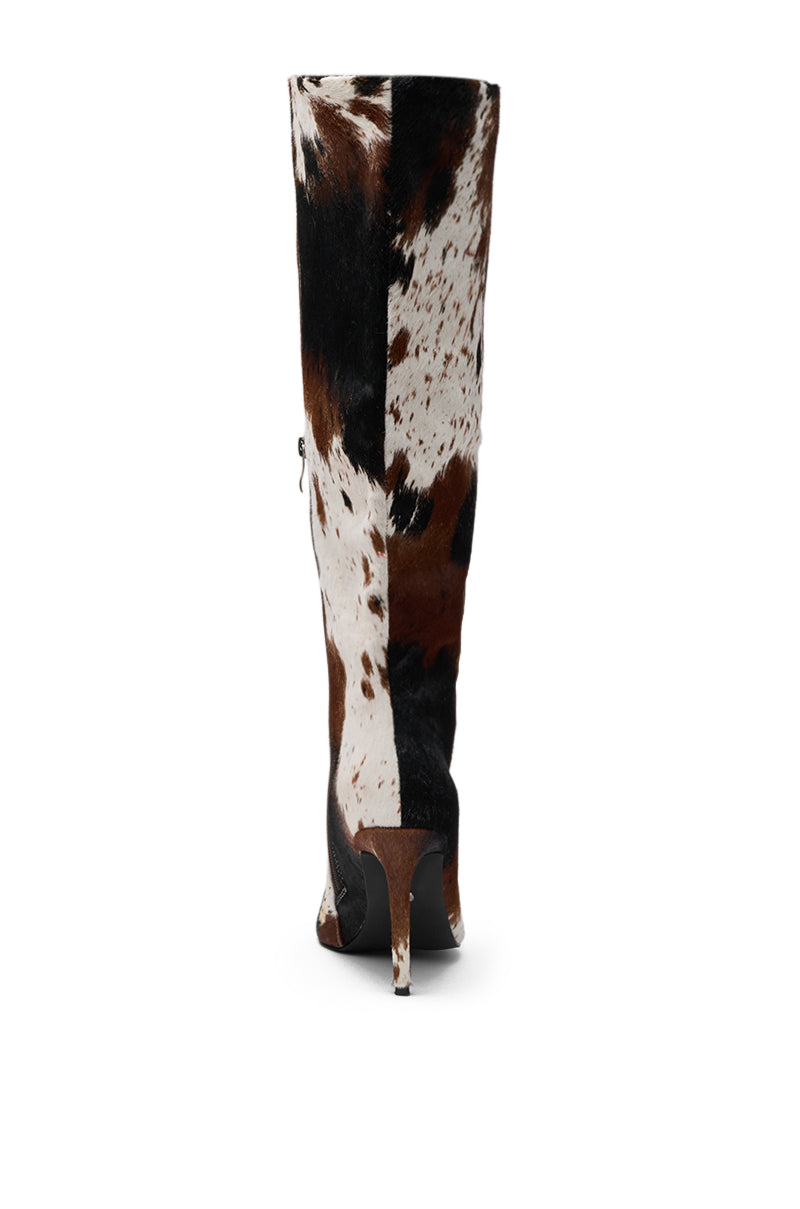 The AZALEA WANG SYREALI COW STILETTO BOOT, a tall knee-high style in black, brown, and white faux cow hair pattern, is displayed from the back against a white background. 6
