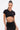 A woman with long dark hair in a high ponytail models the TOO SEXY FOR THIS BODYSUIT, featuring black cut-out details with gold accents. She pairs it with a high-waisted skirt and gold accessories against a plain white background.