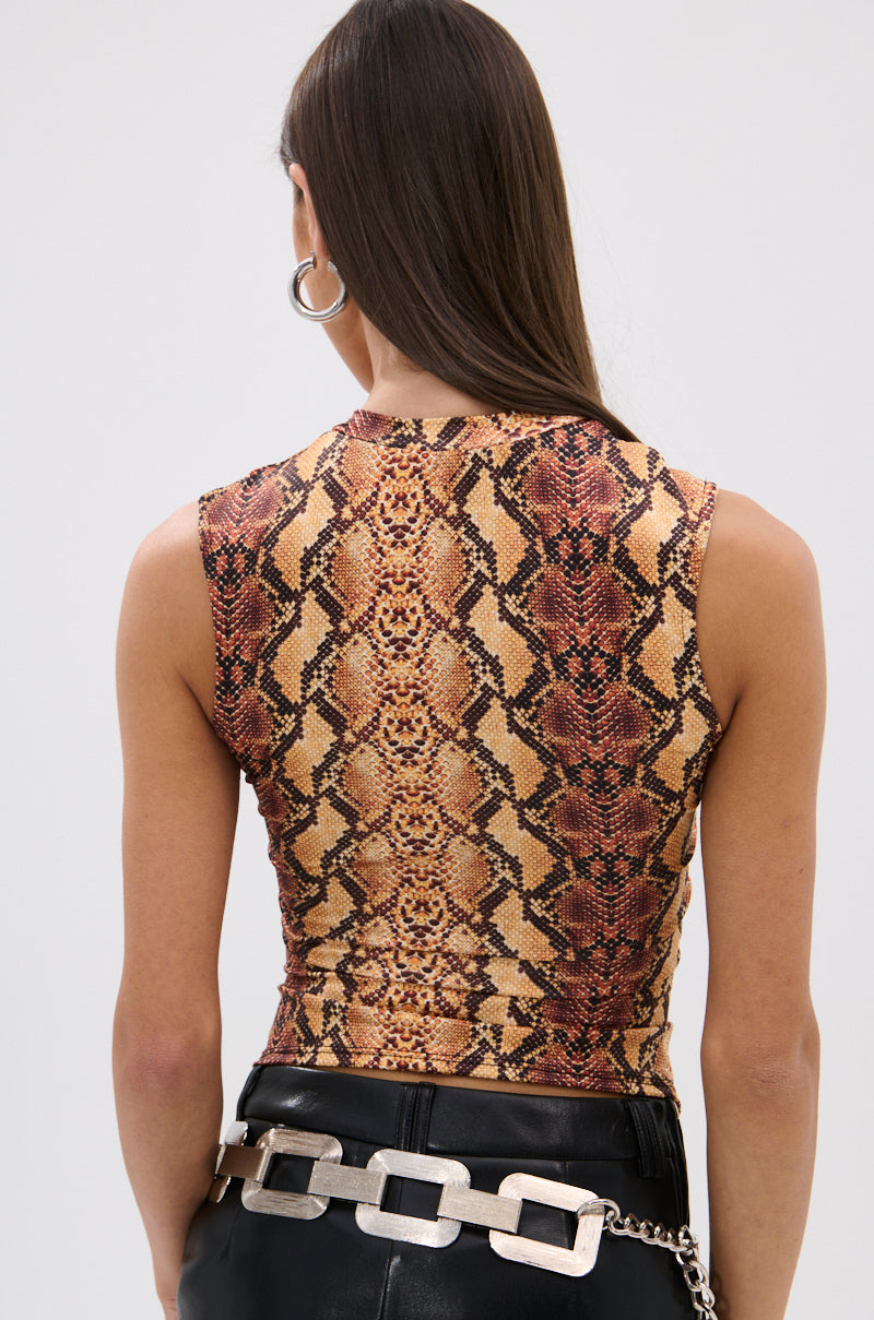 A woman with long brown hair wears the RATTLESNAKE LACE UP TOP and black leather pants with a chain belt, facing away from the camera to highlight the top’s curve-hugging silhouette against a plain background.