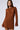 A woman with long brown hair wears the COOL IT KNIT MINI DRESS, a knitted, form-fitting autumn dress featuring vertical ribbed patterns. She has a neutral expression and stands in front of a plain, light background.