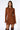 A woman with long brown hair is wearing the COOL IT KNIT MINI DRESS, a fitted, long-sleeved mini dress. She accessorizes with a gold necklace and pairs the outfit with knee-high brown boots. Perfect for fall fashion, the background is plain white.