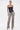 A woman poses confidently in the KIMMY LACE UP DENIM CORSET paired with distressed, light-wash jeans, hoop earrings, and heeled sandals against a plain white background.