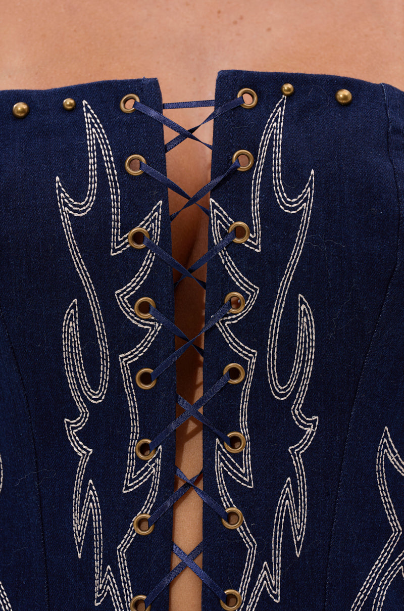 Close-up of the KIMMY LACE UP DENIM CORSET in navy blue with white stitching, bronze studs, and crisscrossed laces at the center revealing skin through the lace-up detail. 8