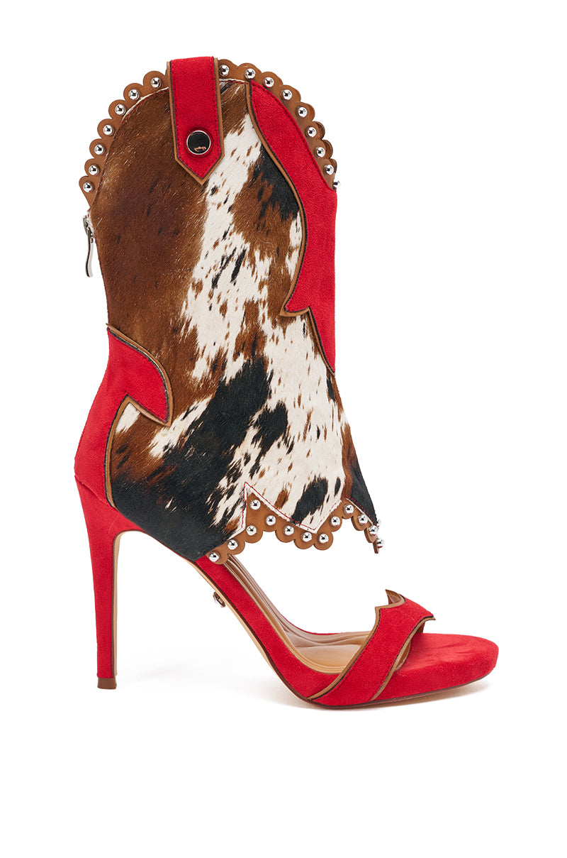 The AZALEA WANG TAHLIE COW MULTI WESTERN GLADIATOR SANDAL features a bold cow print upper in brown, black, and white patches, a red suede sole and strap, stiletto heel, silver eyelets, and western-inspired scalloped edges. 6