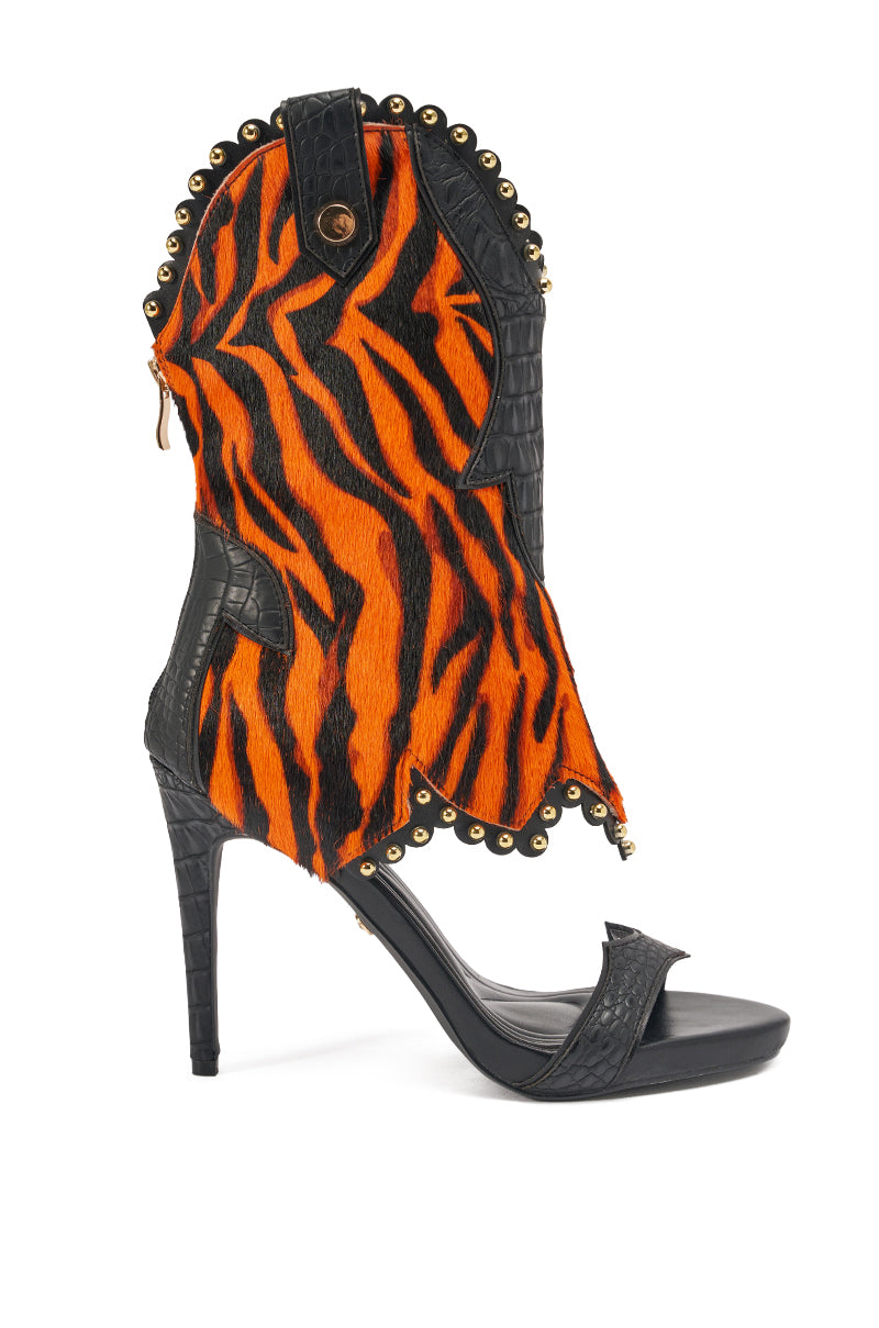 The AZALEA WANG TAHLIE ORANGE MULTI WESTERN GLADIATOR SANDAL is a high-heeled women's style with black faux-crocodile leather, orange-and-black tiger stripes, gold studs, genuine calf hair accents, and an open toe.
