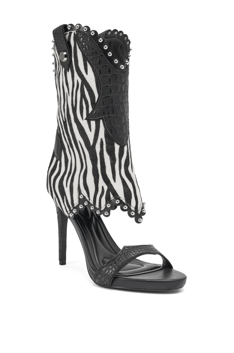 The AZALEA WANG TAHLIE ZEBRA MULTI WESTERN GLADIATOR SANDAL features a bold zebra print, stiletto heel, black faux leather, scalloped edges, silver studs, open toe, and a cowboy boot-inspired upper for a unique gladiator look.