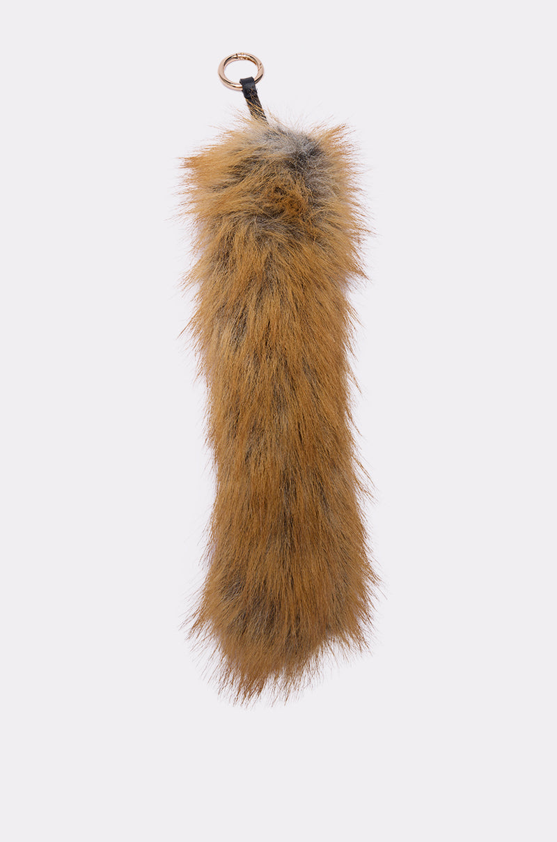The THAT GURL FAUX FUR KEYCHAIN features fluffy brown and black faux fur with a gold-tone hoop clasp and metal ring at the top, shown on a plain light background. 2