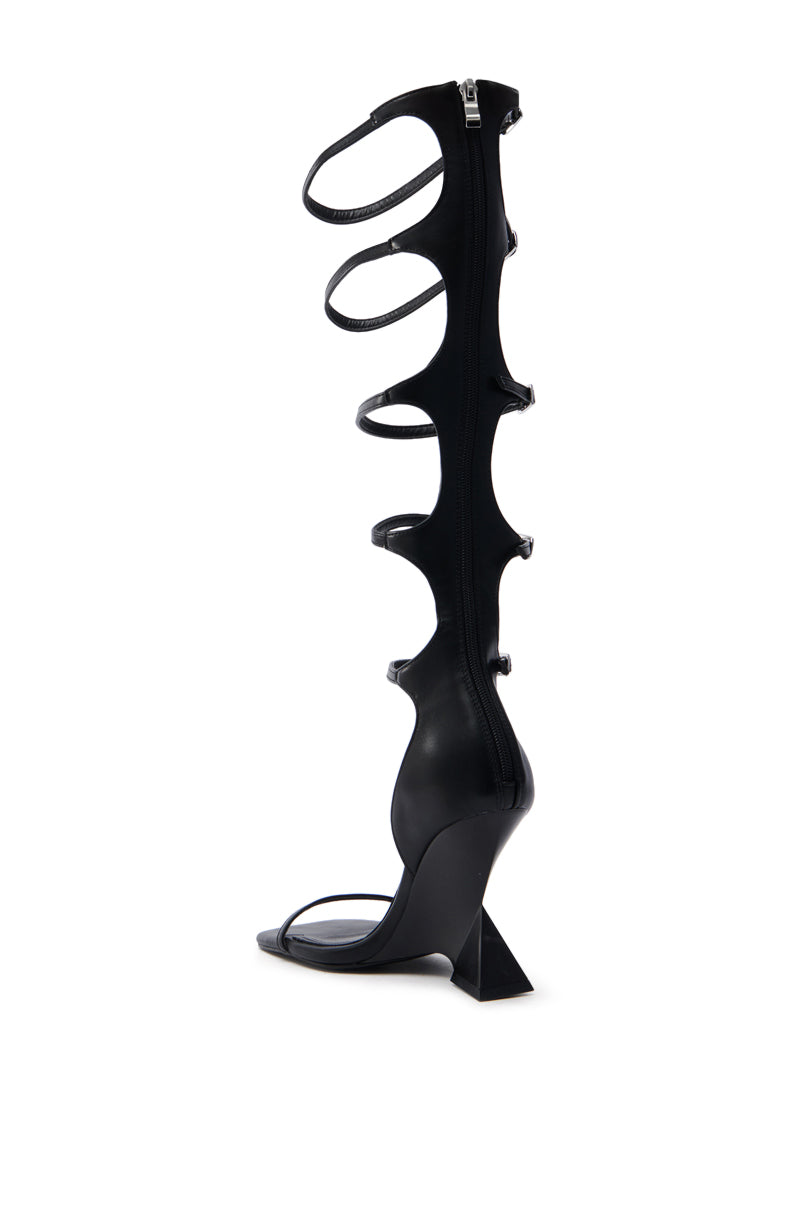 The AZALEA WANG TAITEN BLACK SANDAL features a black, high-heeled design made from vegan leather with an open-toe, multiple straps, and a unique knee-high spine structure. Its geometric heel and comfort cushion insole create a sleek look ideal for any fashion-forward wardrobe.